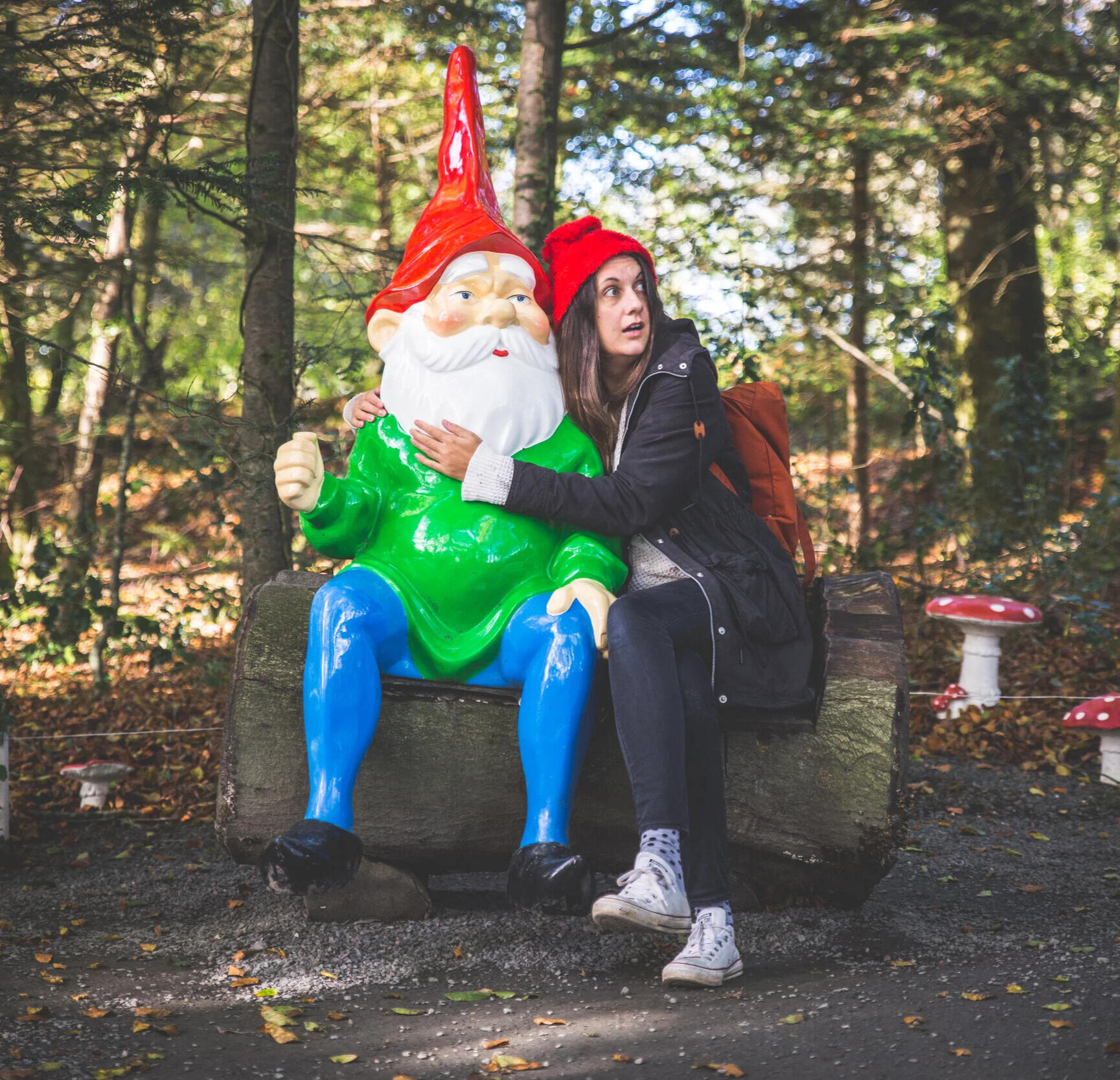 hug a gnome woman wearing a gnome hat looking shocked and hugging a giant gnome